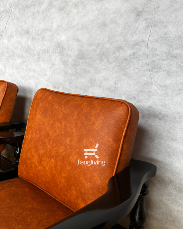 Tampilan dekat bagian sandaran jok kursi tamu klasik dengan material kulit sintetis dan warna oranye kecoklatan