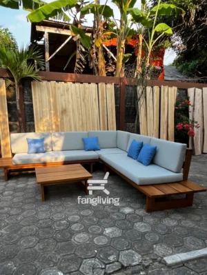 Sofa L jati dengan busa abu dan bantal biru di area outdoor