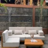 Sofa sudut kayu jati dengan bantalan putih dan meja kayu minimalis